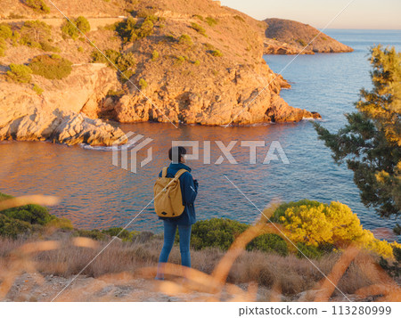 Young woman hiking on rocky beach in Spain, Benidorm. Watching the choppy sea and the bay. traveler enjoying freedom in serene nature landscape Young woman hiking on rocky beach in Spain, Benidorm. Watching the choppy sea and the bay. traveler enjoying freedom in serene nature landscape 113280999