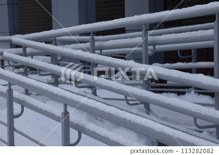 Snow stuck to the shiny light metal railing at the entrance of a residential building Snow stuck to the shiny light metal railing at the entrance of a residential building 113282082