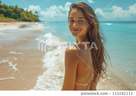 A girl walks along a perfect beach with blue water along the shore. Side view, girl in a light bikini. The girl turns around and winks at the camera. 113282113