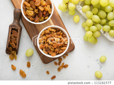 Sweet green raisins in bowl and scoop with grapes in wooden box on light kitchen background. 113282577