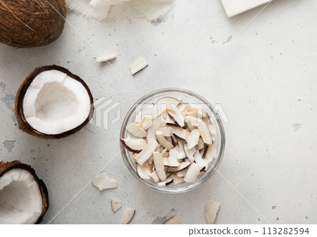 Dried sweet coconut slices chips in glass bowl on light background. 113282594