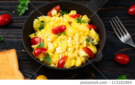 Healthy vegetarian breakfast . Scrambled eggs in pan with cherry tomatoes and parsley Healthy vegetarian breakfast . Scrambled eggs in pan with cherry tomatoes and parsley 113282864