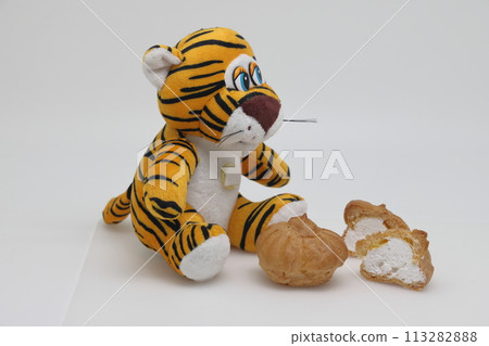 A toy tiger sits in front of sweets. Diet violation. Weight control. A toy tiger sits in front of sweets. Diet violation. Weight control. 113282888