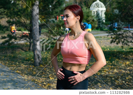 An athlete in comfortable sportswear. Outdoor fitness in the city. Healthy lifestyle. Coach exercises on the street. A confident woman does a workout. An athlete in comfortable sportswear. Outdoor fitness in the city. Healthy lifestyle. Coach exercises on the street. A confident woman does a workout. 113282986