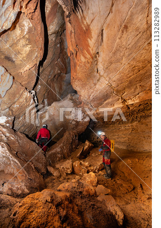 A group of speleologist inside a cave, illuminated by headlamps, exploring the depths of a 113282989