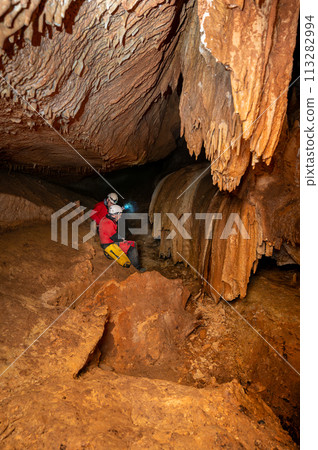 A group of speleologist inside a cave, illuminated by headlamps, exploring the depths of a 113282994