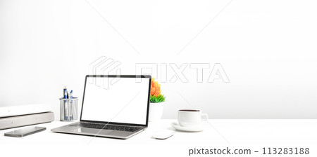 Blank white screen laptop on a white table in the office. Working concept using technology smartphones, notebook, coffee cup. Copy space on right for design or text, Closeup, Gray, and blur background 113283188