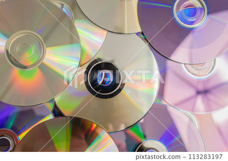 Many old CDs represent technology from the 90s. Stacks of CDs, old songs and old movies. which had been used before and placed on a white table. closeup, selective focus 113283197
