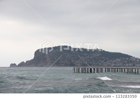 A lone figure in front of foam waves and a historic mountain in Alanya, November 2021. A lone figure in front of foam waves and a historic mountain in Alanya, November 2021. 113283350