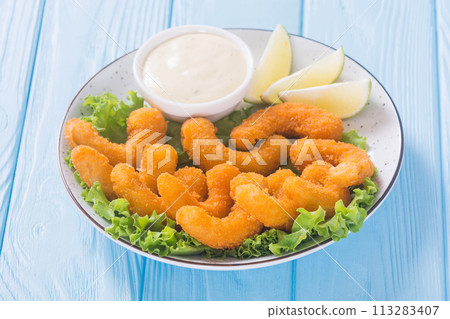 Shrimps in batter with sauce and lime 113283407
