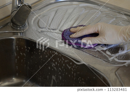 A woman in rubber gloves cleans the sink with detergent. House cleaning. A woman in rubber gloves cleans the sink with detergent. House cleaning. 113283481