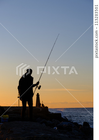 A man standing and fishing at the Kyrenia Harbour at the blue hour in Cyprus 113283501