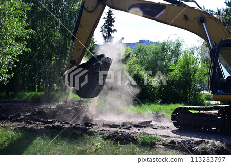Excavator during earthmoving at open pit on blue sky background. Construction machinery and earth-moving heavy equipment for excavation, loading, lifting and hauling of cargo on job sites 113283797