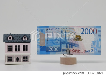The toy house stands next to the banknote on the stand. Accurate financial calculation when buying a property. The toy house stands next to the banknote on the stand. Accurate financial calculation when buying a property. 113283821
