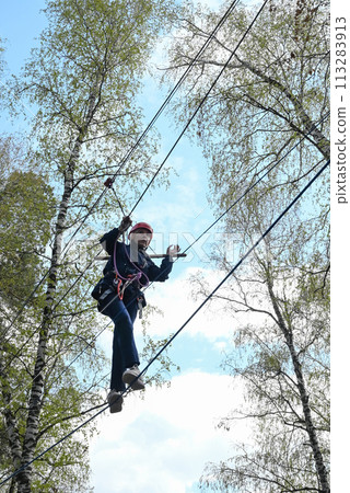 a teenage girl passes an obstacle in a rope park 113283913