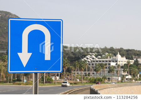 U turn road sign on a metal pole against the backdrop of residential development U turn road sign on a metal pole against the backdrop of residential development 113284256