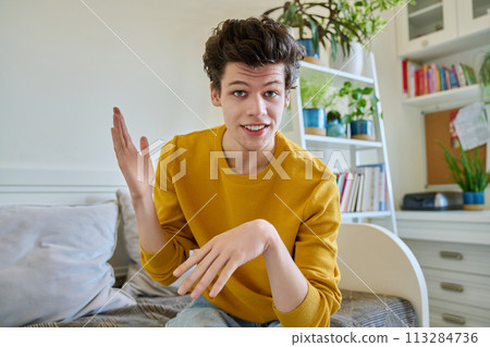 Web camera view of young guy 19-20 years old talking looking at camera in home Web camera view of young guy 19-20 years old talking looking at camera in home 113284736