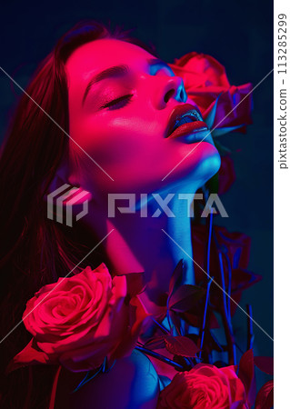 Neon light fashion portrait with flowers. Female model with red roses Neon light fashion portrait with flowers. Female model with red roses 113285299