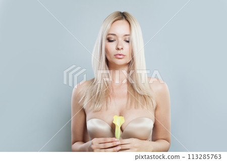 Good-looking young woman with make-up and long blonde hair against white studio wall background 113285763