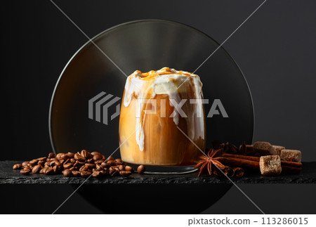 Iced coffee with whipped cream and caramel sauce on a black background. Iced coffee with whipped cream and caramel sauce on a black background. 113286015