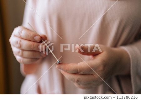Close-up hands of unrecognizable female artisan craftperson holding special tool to mixing dry soy wax for creating candle building mixture. Process of making handmade natural scented candle. Close-up hands of unrecognizable female artisan craftperson holding special tool to mixing dry soy wax for creating candle building mixture. Process of making handmade natural scented candle. 113286216