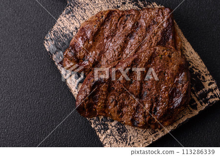 Fresh juicy delicious beef steak on a dark background 113286339