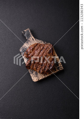 Fresh juicy delicious beef steak on a dark background 113286343