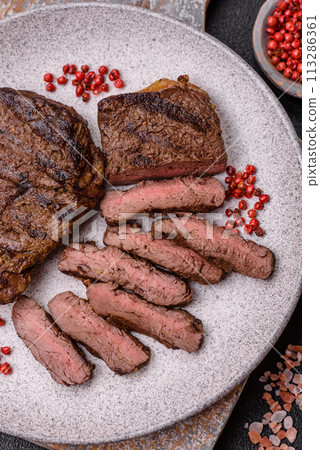 Fresh juicy delicious beef steak on a dark background Fresh juicy delicious beef steak on a dark background 113286361