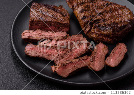 Fresh juicy delicious beef steak on a dark background Fresh juicy delicious beef steak on a dark background 113286362