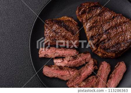 Fresh juicy delicious beef steak on a dark background Fresh juicy delicious beef steak on a dark background 113286363