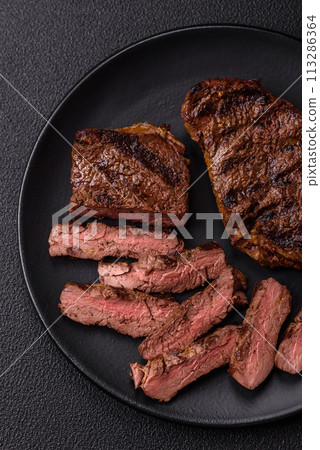 Fresh juicy delicious beef steak on a dark background Fresh juicy delicious beef steak on a dark background 113286364
