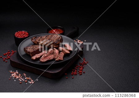 Fresh juicy delicious beef steak on a dark background Fresh juicy delicious beef steak on a dark background 113286368