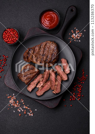 Fresh juicy delicious beef steak on a dark background Fresh juicy delicious beef steak on a dark background 113286370