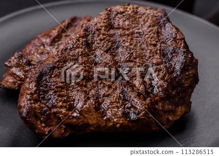 Fresh juicy delicious beef steak on a dark background Fresh juicy delicious beef steak on a dark background 113286515