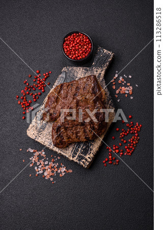 Fresh juicy delicious beef steak on a dark background Fresh juicy delicious beef steak on a dark background 113286518