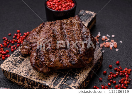 Fresh juicy delicious beef steak on a dark background Fresh juicy delicious beef steak on a dark background 113286519