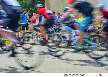 Abstract arty background: motion blur of bicycle racers competing on city streets. Tour of cycling. Blurry background sport with cyclists 113287613