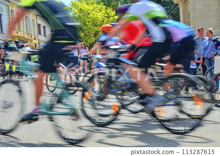 Abstract arty background: motion blur of bicycle racers competing on city streets. Tour of cycling. Blurry background sport with cyclists Abstract arty background: motion blur of bicycle racers competing on city streets. Tour of cycling. Blurry background sport with cyclists 113287615
