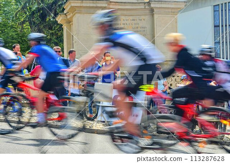 Abstract arty background: motion blur of bicycle racers competing on city streets. Tour of cycling. Blurry background sport with cyclists Abstract arty background: motion blur of bicycle racers competing on city streets. Tour of cycling. Blurry background sport with cyclists 113287628