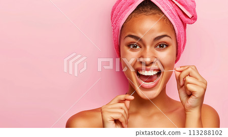 A young woman with bright pink towel on her head happily practices oral hygiene, cleans her gums and teeth with dental floss. The concept of taking care of your health, preventing dental diseases A young woman with bright pink towel on her head happily practices oral hygiene, cleans her gums and teeth with dental floss. The concept of taking care of your health, preventing dental diseases 113288102