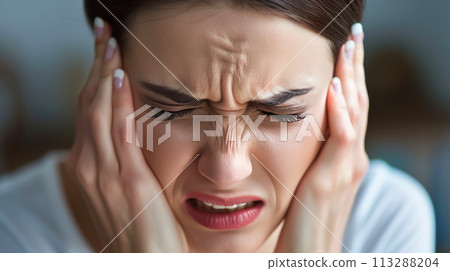 A young woman suffering from a terrible headache holds her head with her hands. Headache, migraine, fatigue, illness, stress A young woman suffering from a terrible headache holds her head with her hands. Headache, migraine, fatigue, illness, stress 113288204
