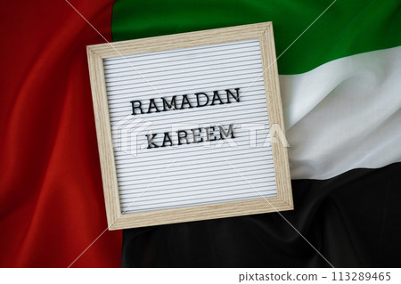Congratulations with text RAMADAN KAREEM - happy holidays waving UAE flag on background concept. Commemoration Day Muslim Greeting card advertisement. Blessed holy month holiday Congratulations with text RAMADAN KAREEM - happy holidays waving UAE flag on background concept. Commemoration Day Muslim Greeting card advertisement. Blessed holy month holiday 113289465