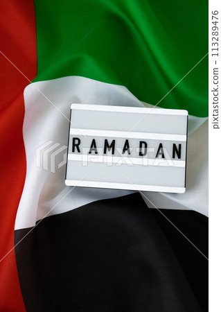 RAMADAN text frame on United Arab Emirates waving flag made from silk material. Public holiday celebration background. Commemoration Day Muslim The National Flag of UAE. Blessed Holy Month concept RAMADAN text frame on United Arab Emirates waving flag made from silk material. Public holiday celebration background. Commemoration Day Muslim The National Flag of UAE. Blessed Holy Month concept 113289476