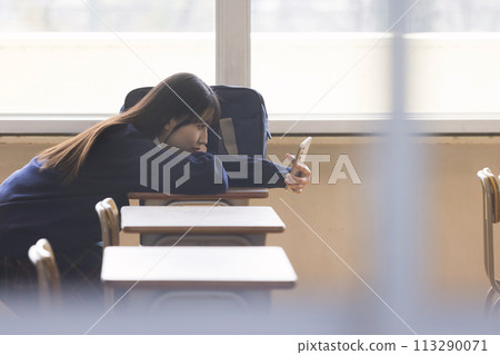 A high school girl looks at her smartphone in the classroom after school 113290071