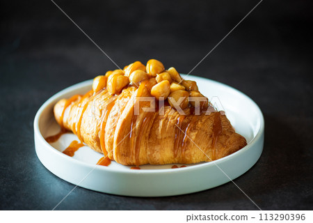 Plate of tasty croissant with chocolate and almond on dark wooden table. French pastry. Plate of tasty croissant with chocolate and almond on dark wooden table. French pastry. 113290396