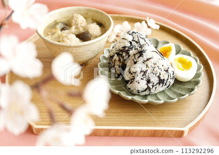 美味的日式早餐，包括飯糰、羊棲菜和味噌湯，裡面有許多配料，粉紅色背景 113292296