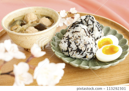 美味的日式早餐，包括飯糰、羊棲菜和味噌湯，裡面有許多配料，粉紅色背景 113292301