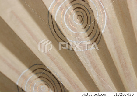A traditional Japanese fan (sensu) made of ivory-colored washi paper with a thin ripple pattern made of gold and silver foil. A traditional Japanese fan (sensu) made of ivory-colored washi paper with a thin ripple pattern made of gold and silver foil. 113293430