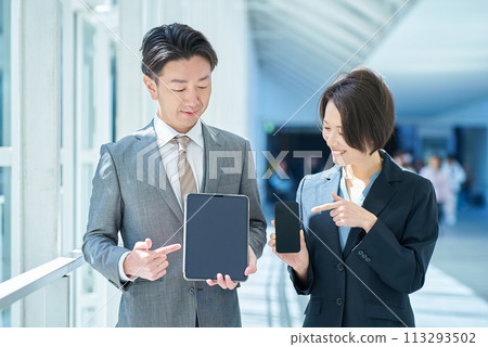 Men and women in suits holding portable digital communication devices 113293502