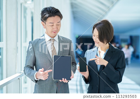 Men and women in suits holding portable digital communication devices 113293503